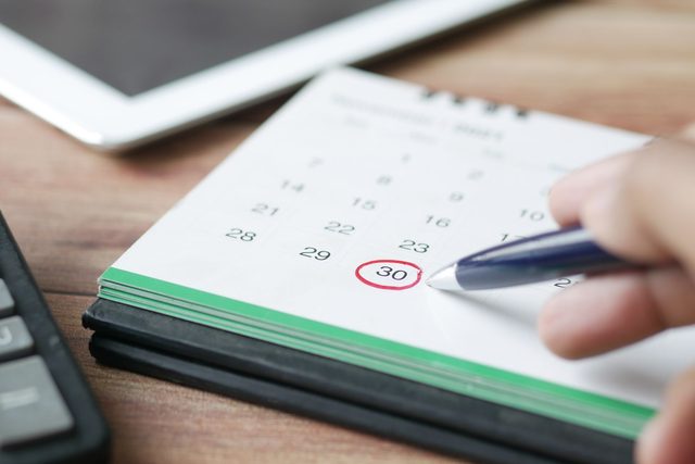 A hand marking an appointment date on a calendar