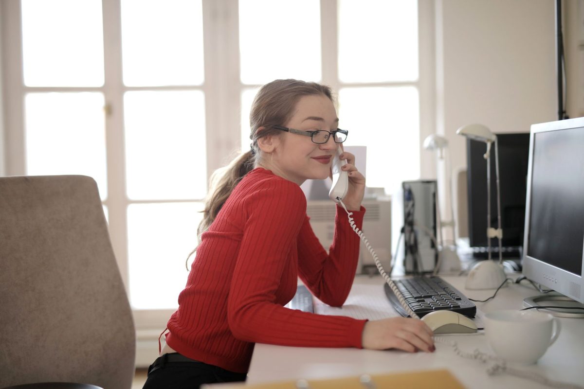 A woman at an office desk talking on a landline phone